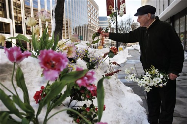Phil Caruso of Caruso Florist, puts flowers in the snow outside the shop in Washington on Thursday. The shop rented four-wheel-drive vehicles to pick up employees and make deliveries in the wake of back-to-back snowstorms.